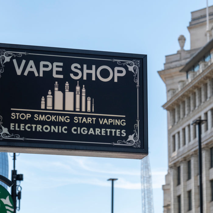 Black sign for a vape shop that includes the message Stop Smoking Start Vaping