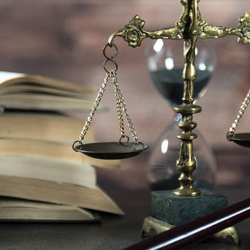 multiple books, scale of justice, and gavel arranged on a table 