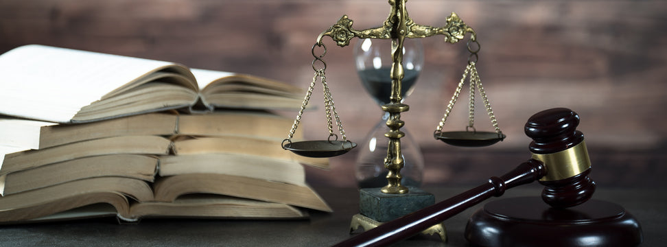 multiple books, scale of justice, and gavel arranged on a table 